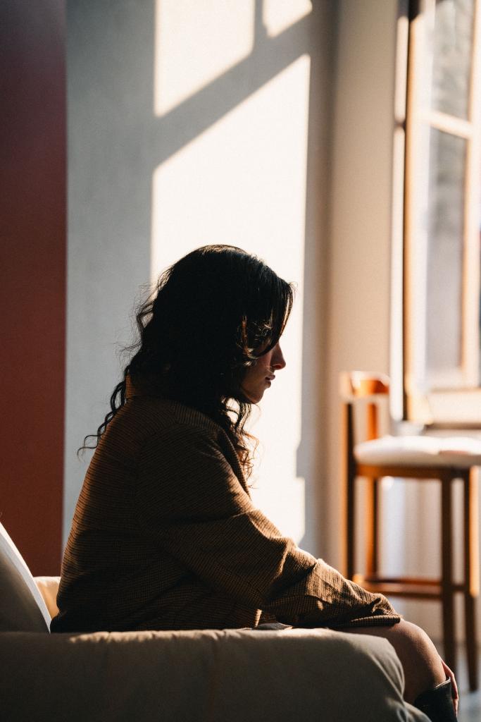 Femme assise seule dans un intérieur lumineux, regard pensif