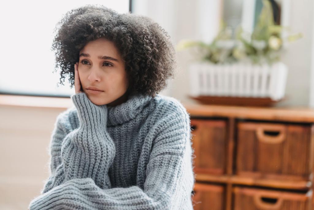 Femme assise au regard pensif et fatigué dans un espace calme, illustrant la confusion et l'épuisement intérieur de ceux qui restent dans une relation qui leur fait du mal.