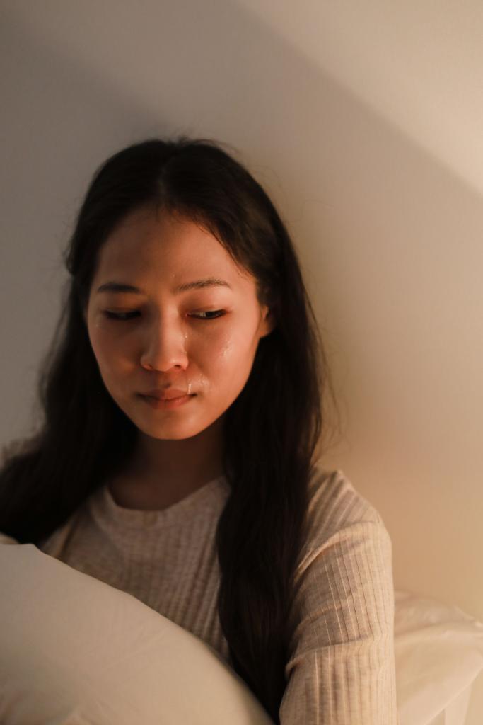 Femme au regard baissé dans un espace calme avec une expression de tristesse contenue, illustrant les pertes invisibles et les deuils non reconnus qu'on ne s'autorise pas à pleurer.