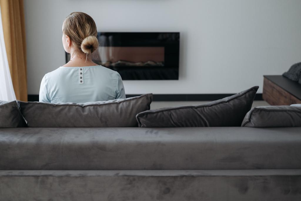 Femme dans un espace intérieur familier et confortable dans une posture de repli, illustrant la zone de confort comme espace rassurant qui peut aussi freiner le changement.