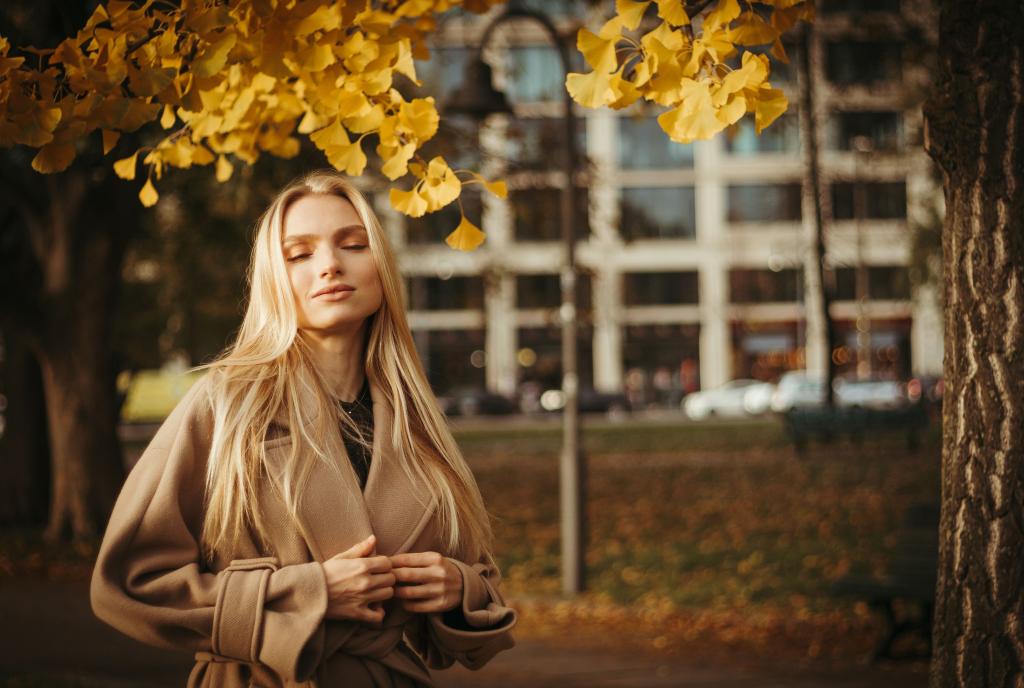 Femme dans un espace naturel automnal dans une posture de relâchement progressif, illustrant le retour au sentiment de sécurité intérieure après un état d'anxiété chronique.