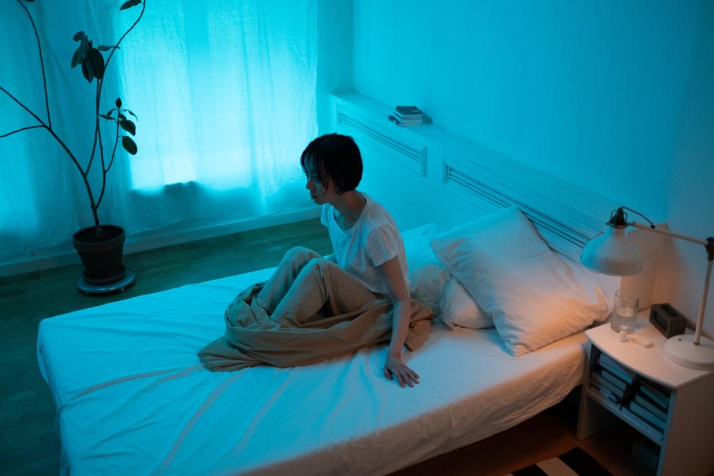 Femme éveillée dans la pénombre d'une chambre ou à l'aube, les yeux ouverts, illustrant les manifestations nocturnes de l'anxiété au quotidien — insomnies et pensées en boucle.
