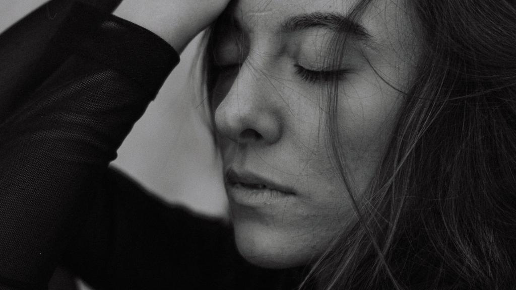 Femme les yeux fermés dans une posture d'épuisement intérieur silencieux, illustrant le coût émotionnel du perfectionnisme chronique.
