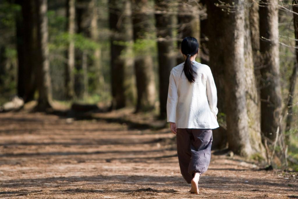 Femme seule dans un espace naturel calme dans une posture détendue, illustrant la solitude choisie comme espace de ressourcement et de retour à soi — thérapie par la marche.