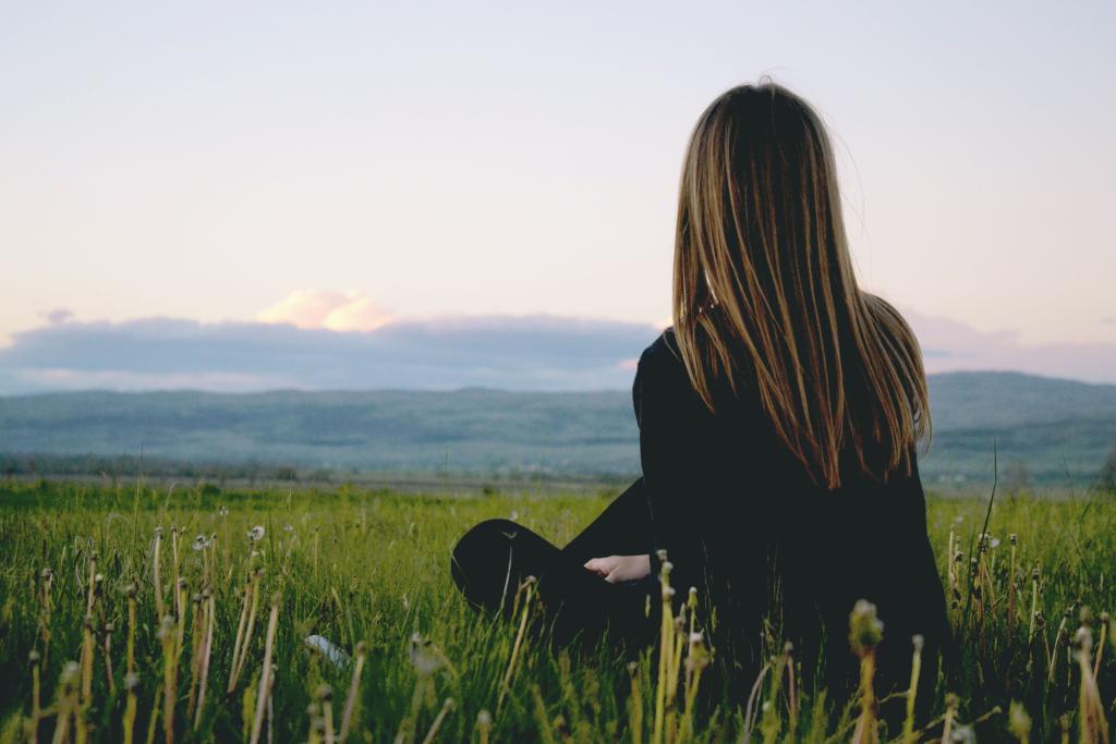 Femme seule dans un espace naturel ouvert dans une posture calme et présente, illustrant le début d'un retour à soi après une relation toxique — thérapie par la marche.