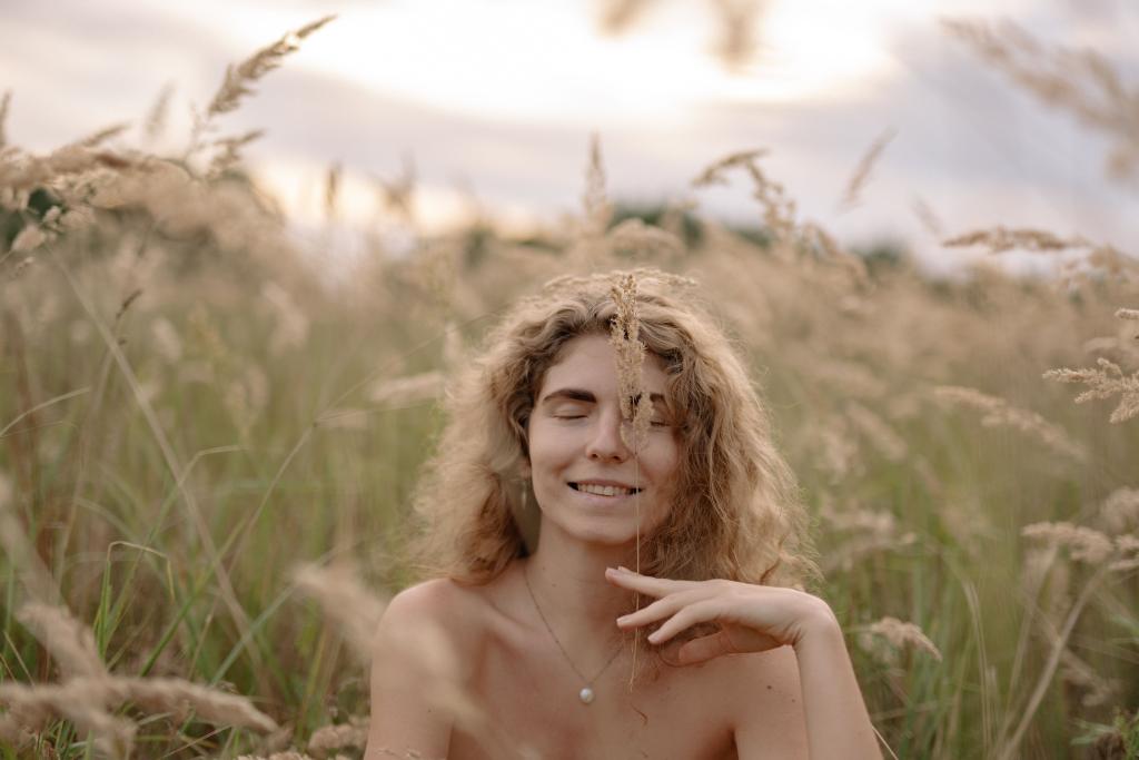 Femme allongée dans l'herbe les yeux fermés, dans une lumière estivale dorée, illustrant le lâcher-prise et la reconnexion à ses besoins profonds en pleine nature.