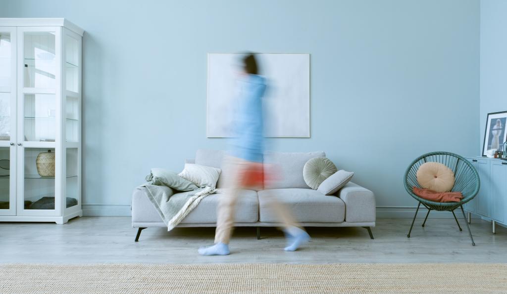 Femme en mouvement dans un espace intérieur, illustrant l'agitation du quotidien et la difficulté à s'arrêter pour reconnaître ses besoins psychologiques.
