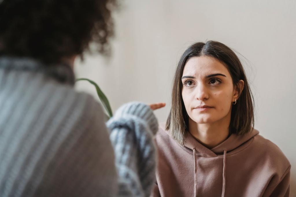 Femme légèrement figée pendant une conversation, regard immobile, illustrant la façon dont la réponse de freeze peut se déclencher dans des situations relationnelles du quotidien — conflits, confrontations, émotions intenses.
