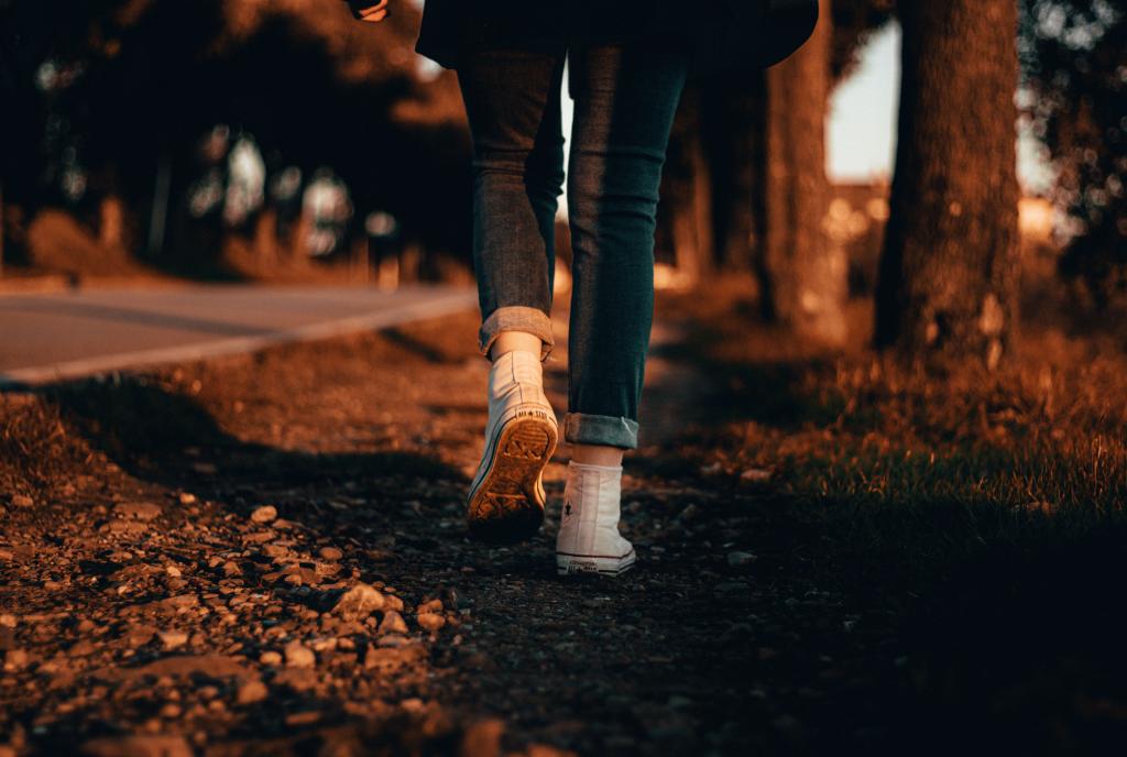 Femme marchant lentement dans un espace naturel automnal, les pieds bien ancrés au sol, illustrant le retour progressif à la présence corporelle après un état de figement — mouvement conscient comme voie de sortie du freeze.