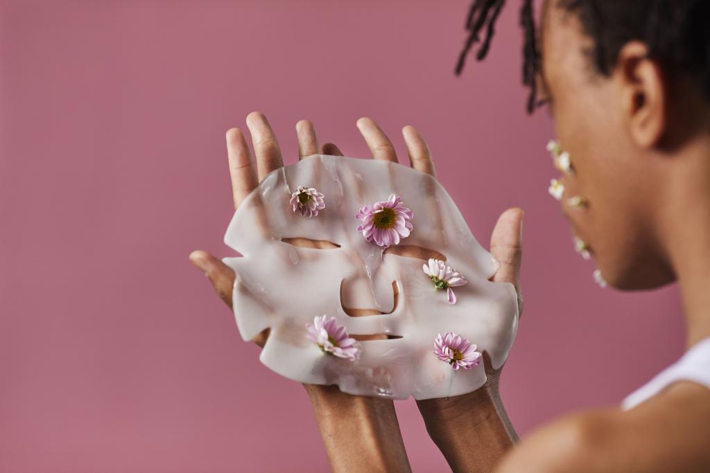 Mains posant un masque blanc sur un fond neutre, illustrant la notion de masque social et de faux self dans la perte de contact avec son identité profonde.