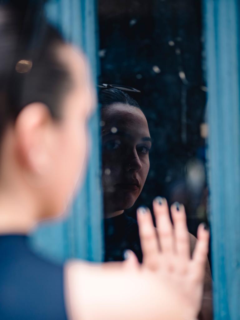 Femme regardant son reflet dans un miroir flou, illustrant la perception déformée de soi liée aux croyances inconscientes.