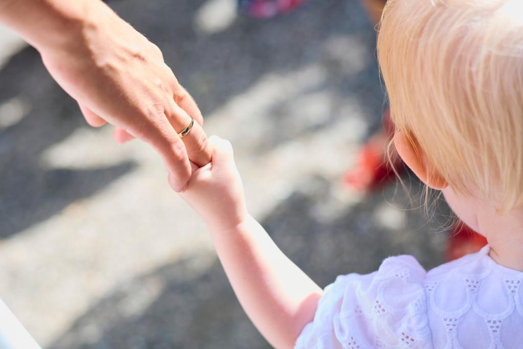 Mains d'adulte guidant un enfant, symbolisant la transmission des croyances et des schémas émotionnels dans l'enfance.