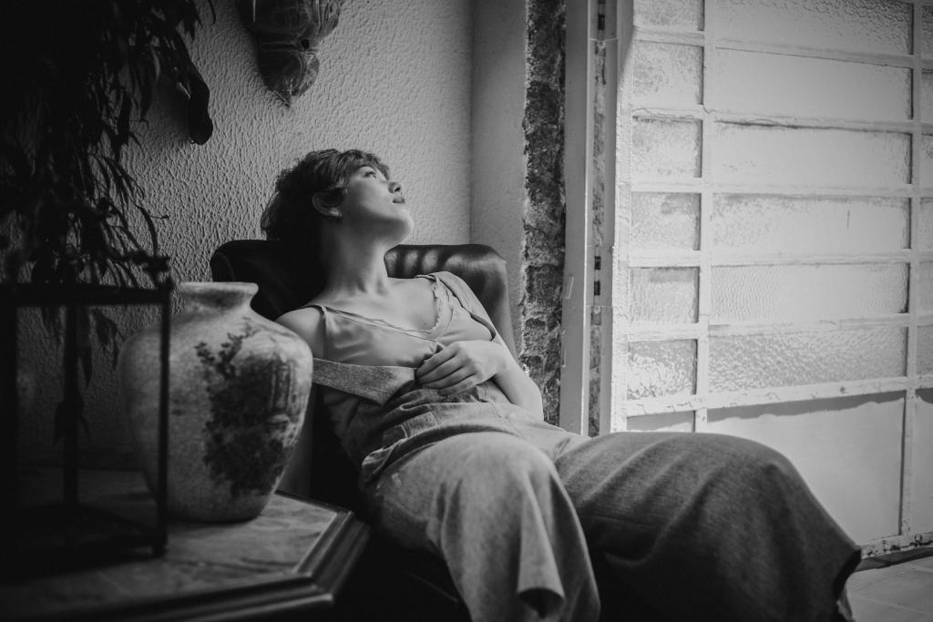 Femme au regard pensif dans un espace intérieur lumineux et calme, illustrant le questionnement identitaire et le sentiment de ne pas savoir qui l'on est.